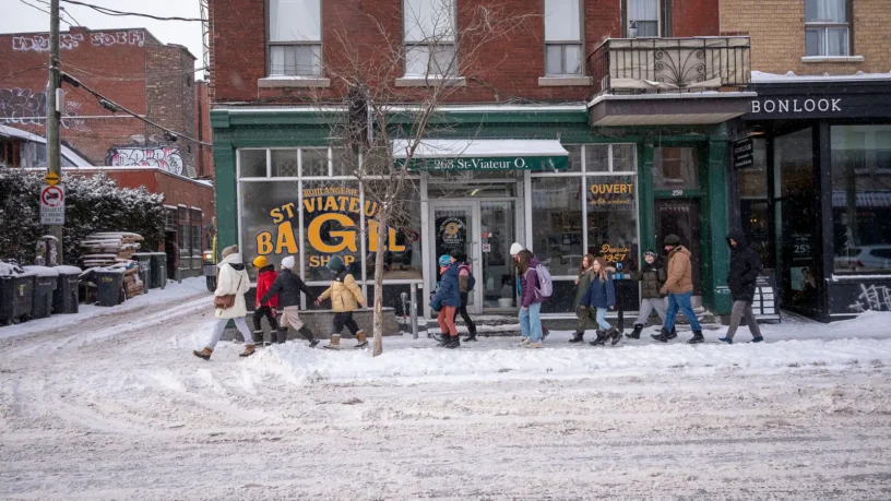Rue enneigée du Mile End, à Montréal, avec des passants devant une boutique, un après-midi d'hiver