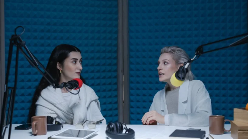 Deux femmes en pleine conversation, micros et casques d'écoute, dans un studio de balado insonorisé